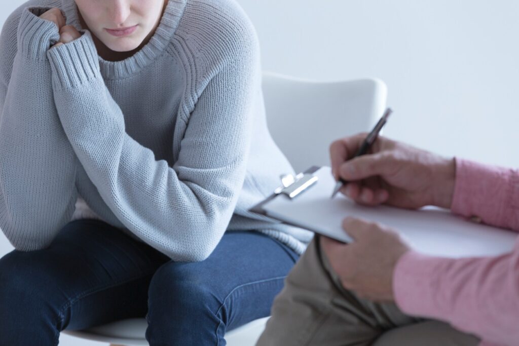 A young woman talks with a therapist during inpatient mental health treatment at Diversus Health.