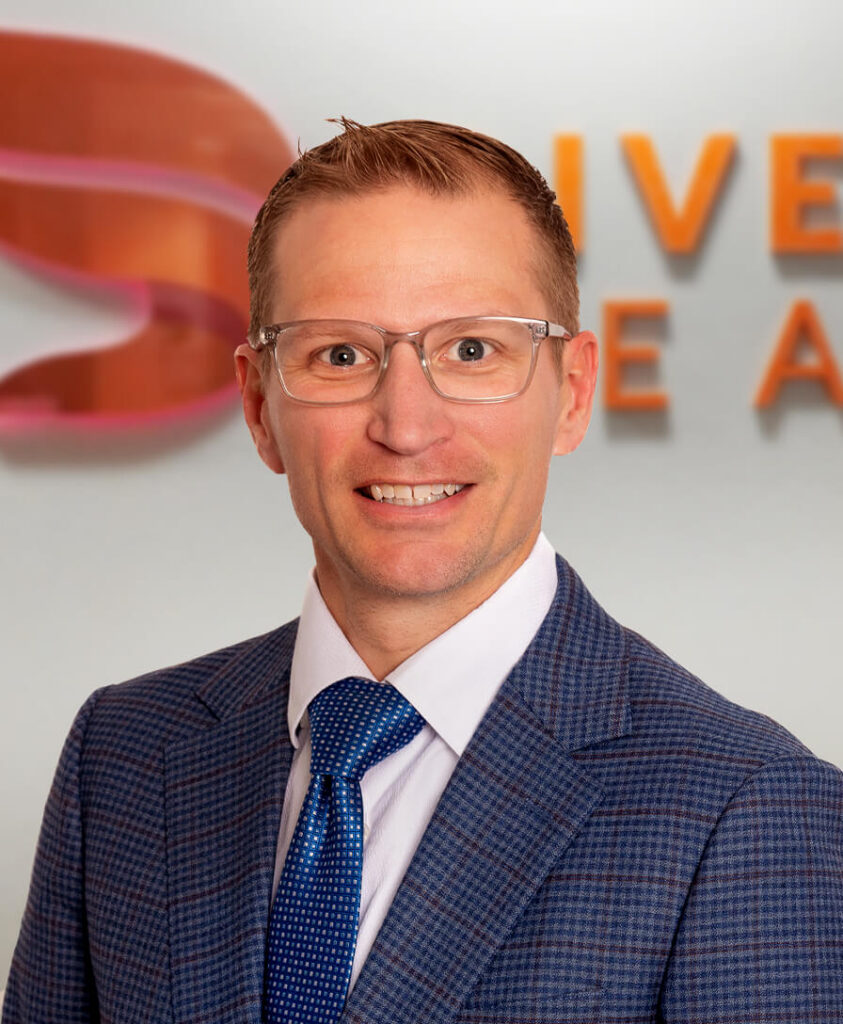 Headshot of Mark Hall, Diversus Health Chief Financial Officer, in front of the orange Diversus Health logo